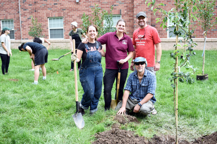 Students, volunteers, professors from university plant orchard at